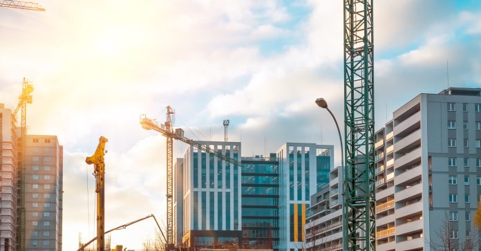 Construction of modern altitudinal buildings of concrete and glass early in the morning during sunrise