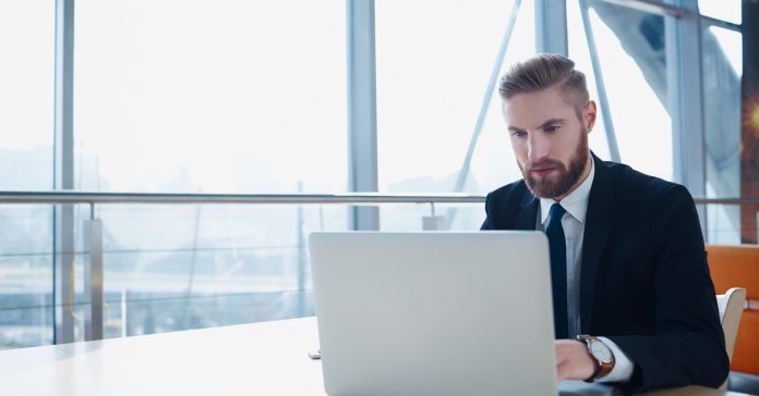 Successful businessman typing on laptop at modern office